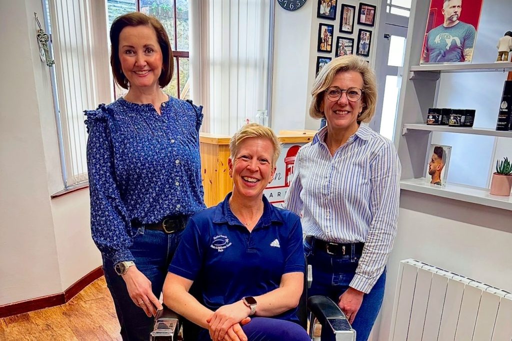 Alan Rowe Barbering group photo of three female staff one seated in a barbers chair