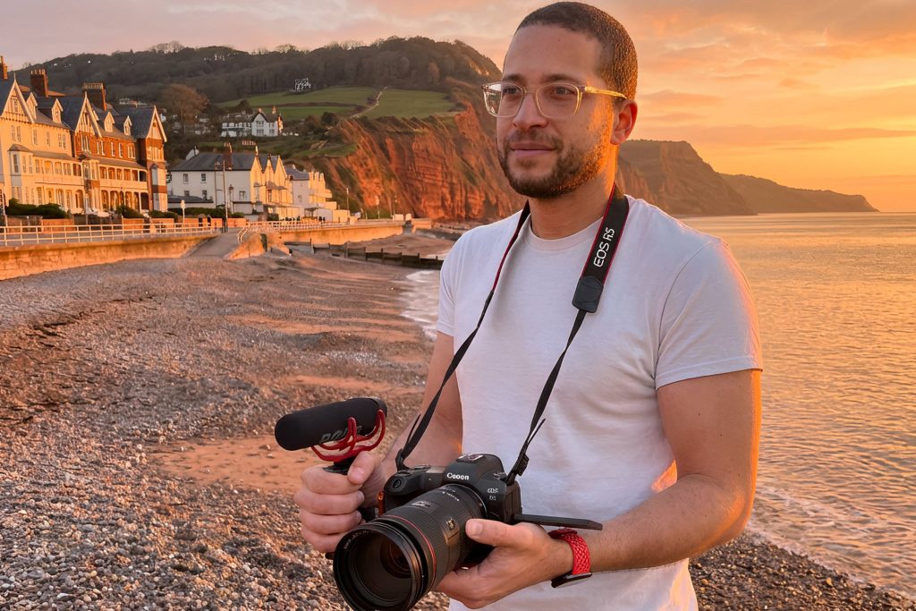Sean Brown on the beach at sunset with Canon camera around his nexk