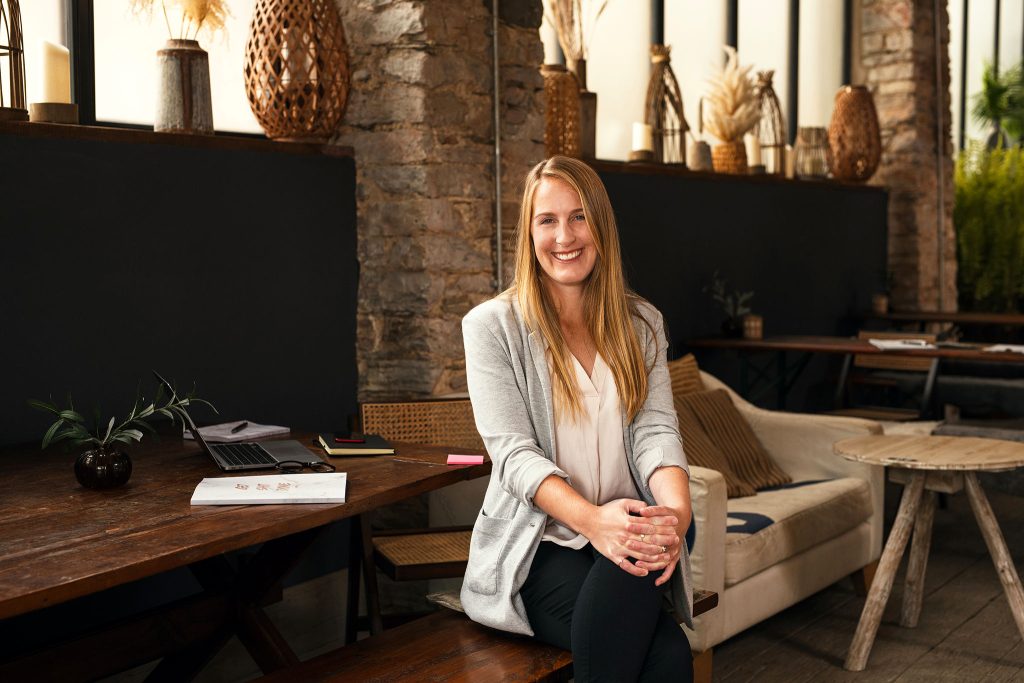 Amy Sugrue of On Point VA sitting on a bench in rustic style office