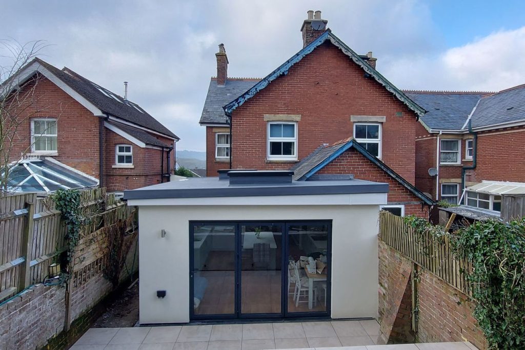 Modern white extension designed by MC Architects at the rear of a traditional red brick house