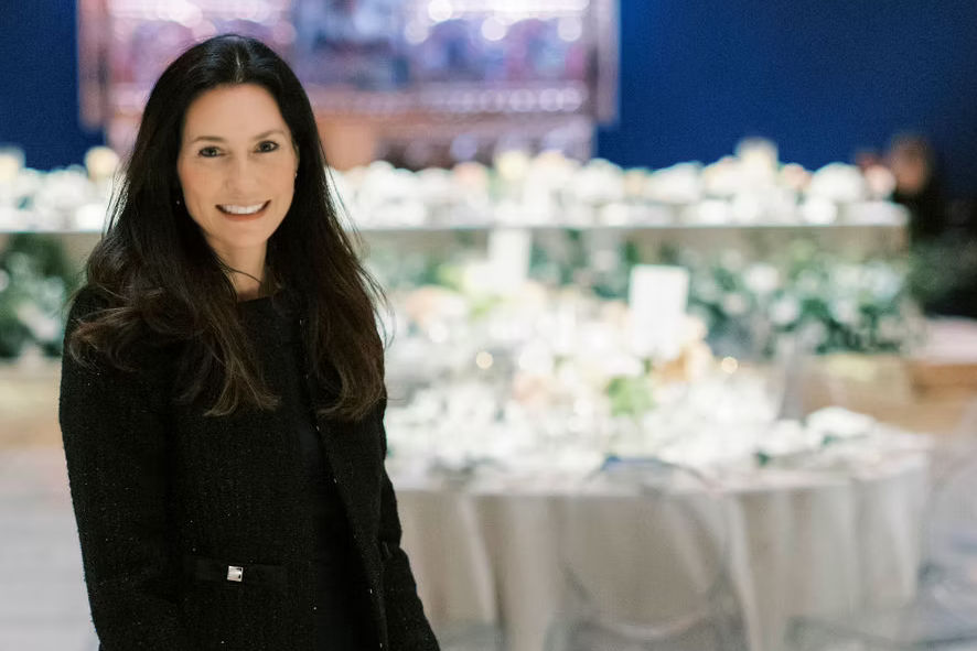 Jessica Kearney of Elite Business Concierge in front of tables set with white tablecloths and perspex chairs.